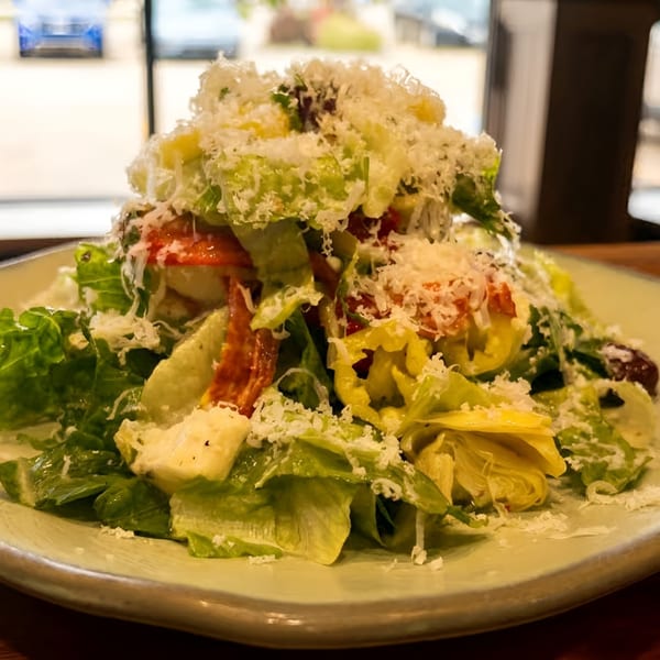 Fresh salad with crisp lettuce, tomatoes, artichokes, olives, and generous grated Parmesan cheese.